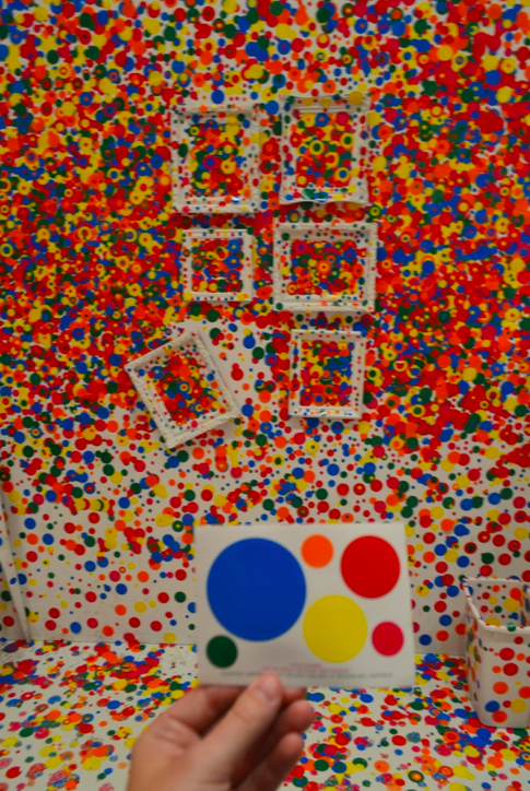 A detail of the six sticker sheet used by the Hirshorn Museum in their Obliteration Room. There are two different sized red stickers, a small orange and green sticker, a medium sized yellow sticker, and a large blue sticker, all circular.
