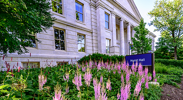 The American University Hurst Hall building with a sign that says Hurst Hall and pink flowers