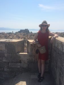 Paige Magrogan wearing wide-brimmed hat and sunglasses, in the Old Citadel of Corfu, Greece.