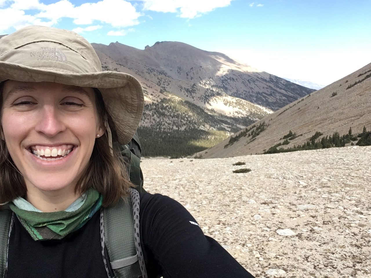 person smiling in a hat on a mountain